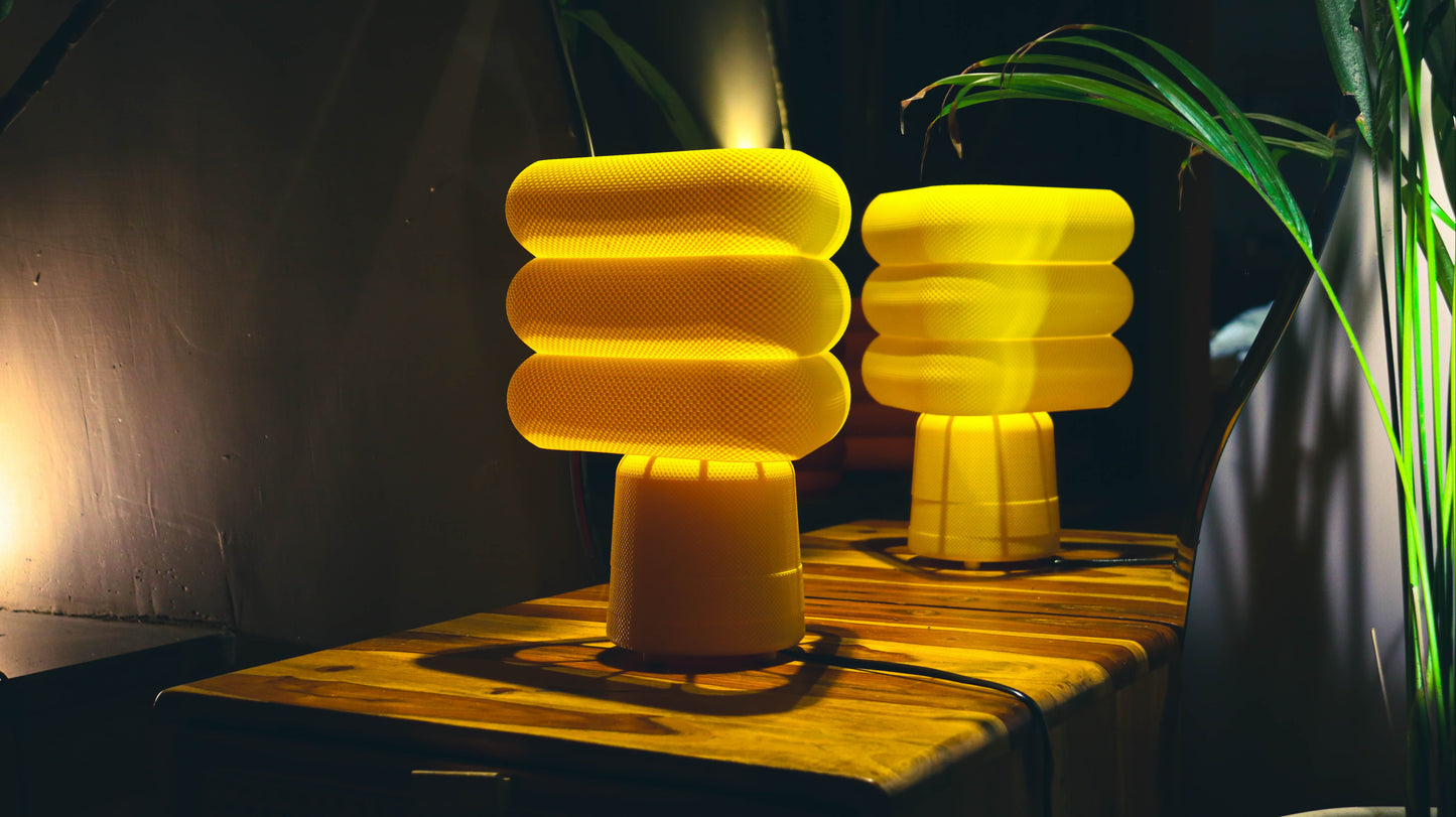 Two yellow lampshades on a wooden surface with a dark background
