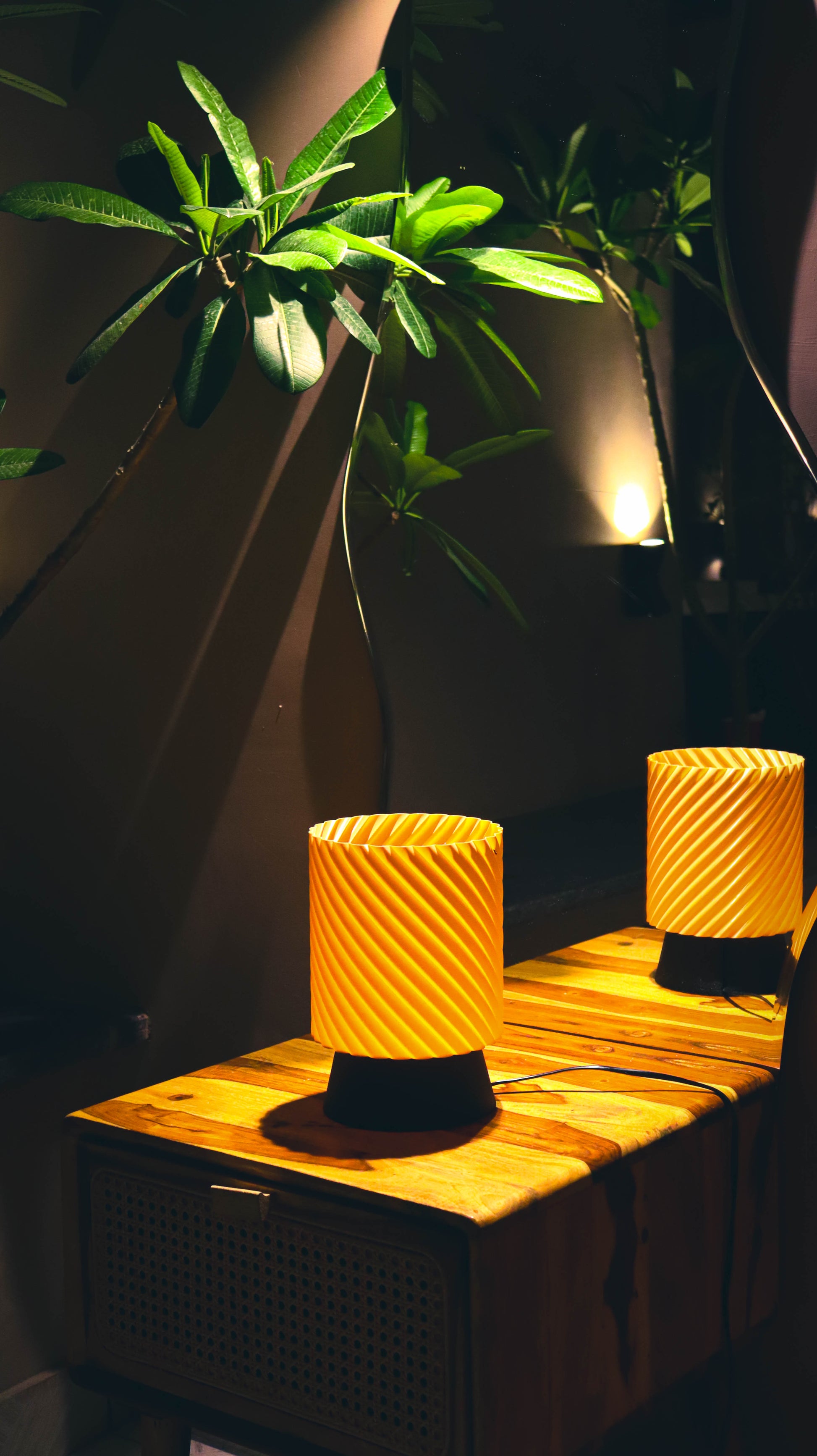 Peach textured lamp on a wooden surface with a plant in the background