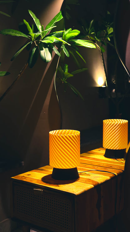 Peach textured lamp on a wooden surface with a plant in the background