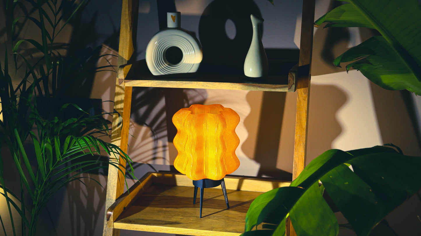 Orange lamp on a wooden shelf with plants and a blurred background