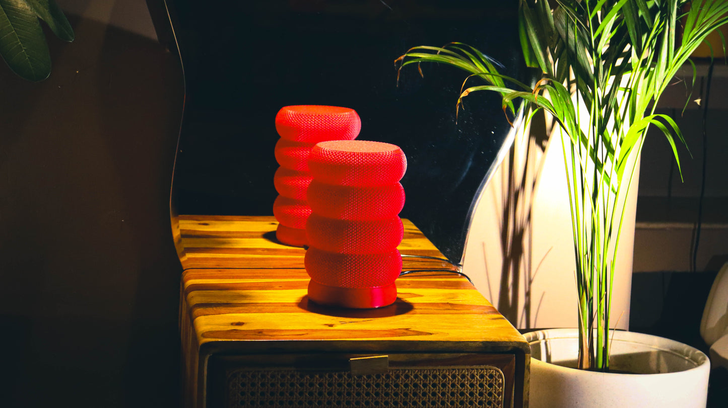 Two red mesh-textured lamps illuminated on rustic wood side table